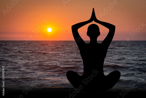 Fototapeta Naklejka Na Ścianę i Meble -  Silhouette of a woman doing yoga exercises on the beach in the sunset