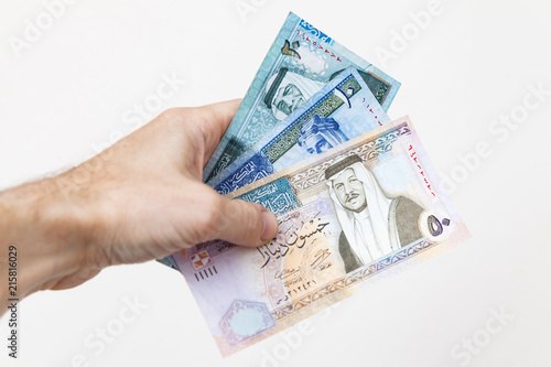 Male hand holding Jordanian dinars