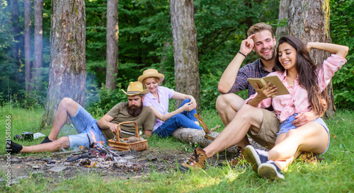 Couples or families having great time relaxing near campfire. Couples spend time outdoors on sunny day. Pleasant weekend. Youth on picnic or hike relaxing and having fun. Couples tourists rest forest
