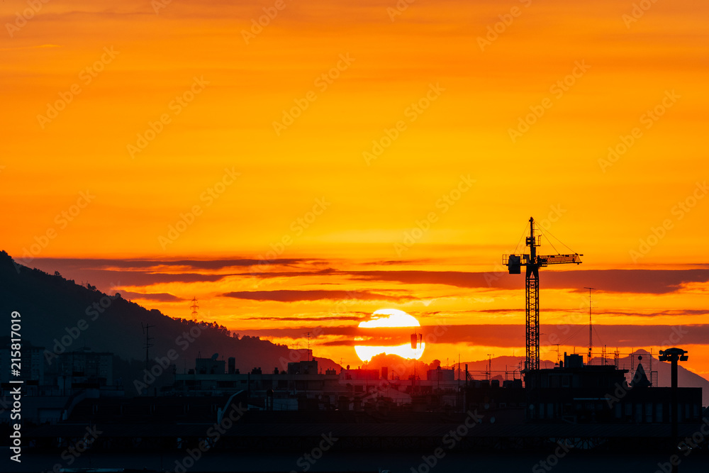 silhouette of construction cranes at sundown