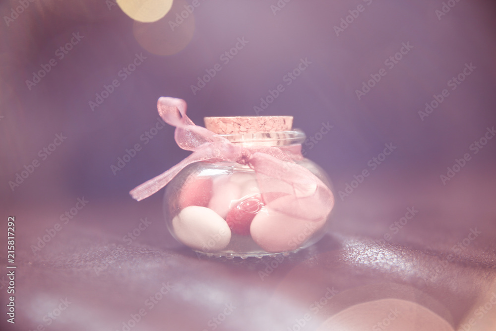 Pink, White and Red Wedding Favours in Small Round Glass Bottle on Dark Leather Sofa. Pink, White and Red Wedding Favours in Small Round Glass Bottle on Dark Leather Sofa.