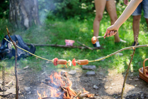 How to roast sausages with vegetables. Sausages on stick bonfire background. Smoky smell of roasted food. Roasty toasty sausages are such quintessential taste of picnic. Roasting food on stick