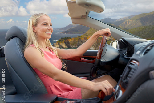 travel, road trip and people concept - happy young woman driving convertible car over bixby creek bridge on big sur coast of california background photo