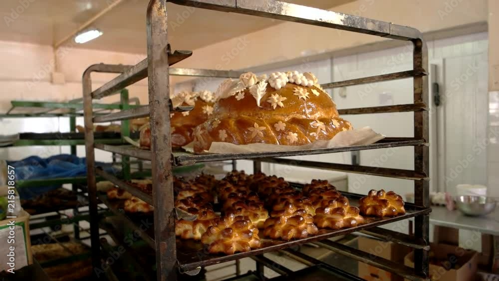 Chef putting round loaf on rack. Rack trolley with freshly baked pastry. Manufacture of baking products. Chef putting round loaf on rack. Rack trolley with freshly baked pastry. Manufacture of baking products.