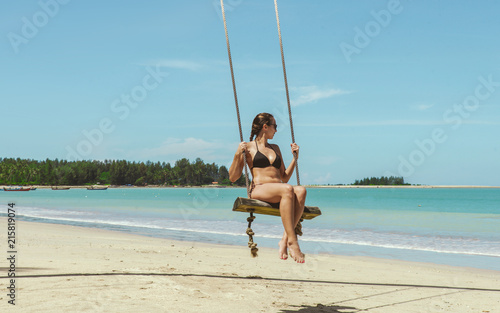 Swinging sexy girl at the beach n front of the tropical sea