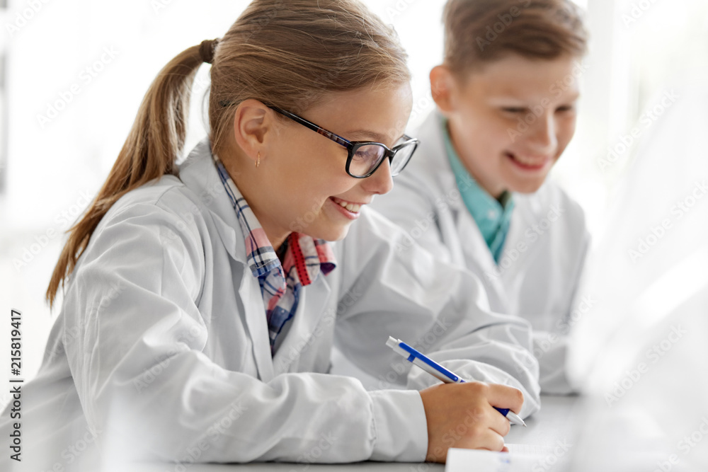 education, science and children concept - close up of happy girl studying chemistry at school laboratory and writing to workbook education, science and children concept - close up of happy girl studying chemistry at school laboratory and writing to workbook