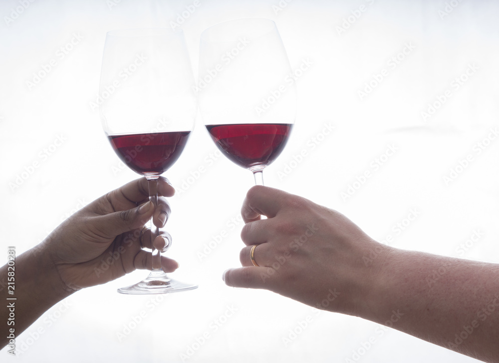 two hands holding wineglasses with red wine