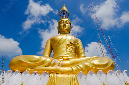 Monumental Buddha figure  gilded  with head umbrella  on top of Tiger rock near Krabi Thailand  and radion antenna in background.