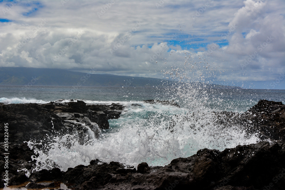Wave crashing over the lava rock coastline of the island of Maui, Hawaii.