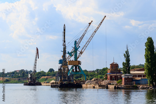 Heavy cranes in cargo port on the riverbank