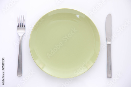 白い木製テーブルに置かれた緑の皿とカトラリー