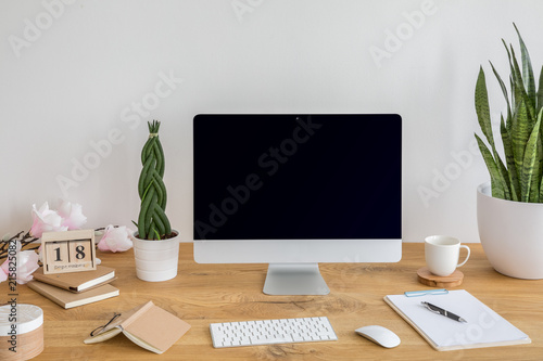 Computer desktop with mockup on wooden desk with books, keyboard and plants in the interior. Real photo © Photographee.eu
