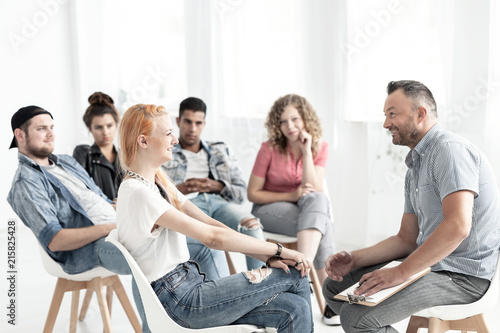 Smiling red-haired girl talking with therapist during meeting for difficult teenagers