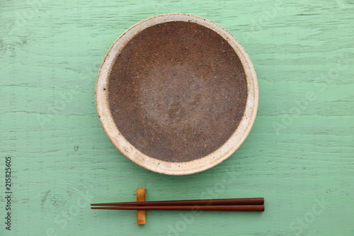 緑のテーブルに置かれた土製の皿と箸