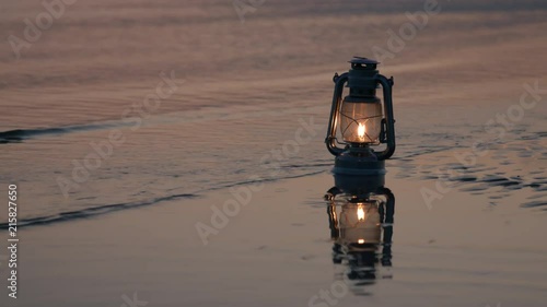 Old vintage kerosene lantern on beach at sunset