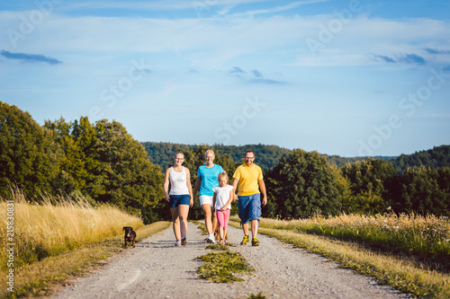 Family walking their dog on a dirt path in summer