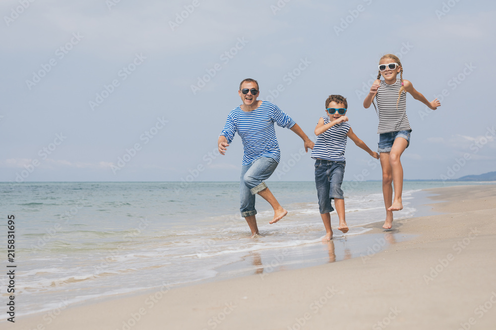 Father and children  playing on the beach at the day time.