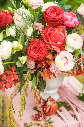 A bouquet of blossoming flowers of roses in a wedding decoration standing in a vase on a pedestal.