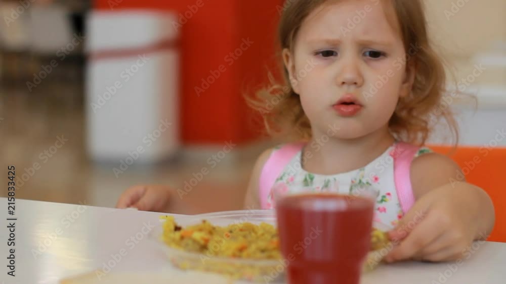 Child girl does not want to eat food in a fast food cafe or restaurant Child girl does not want to eat food in a fast food cafe or restaurant