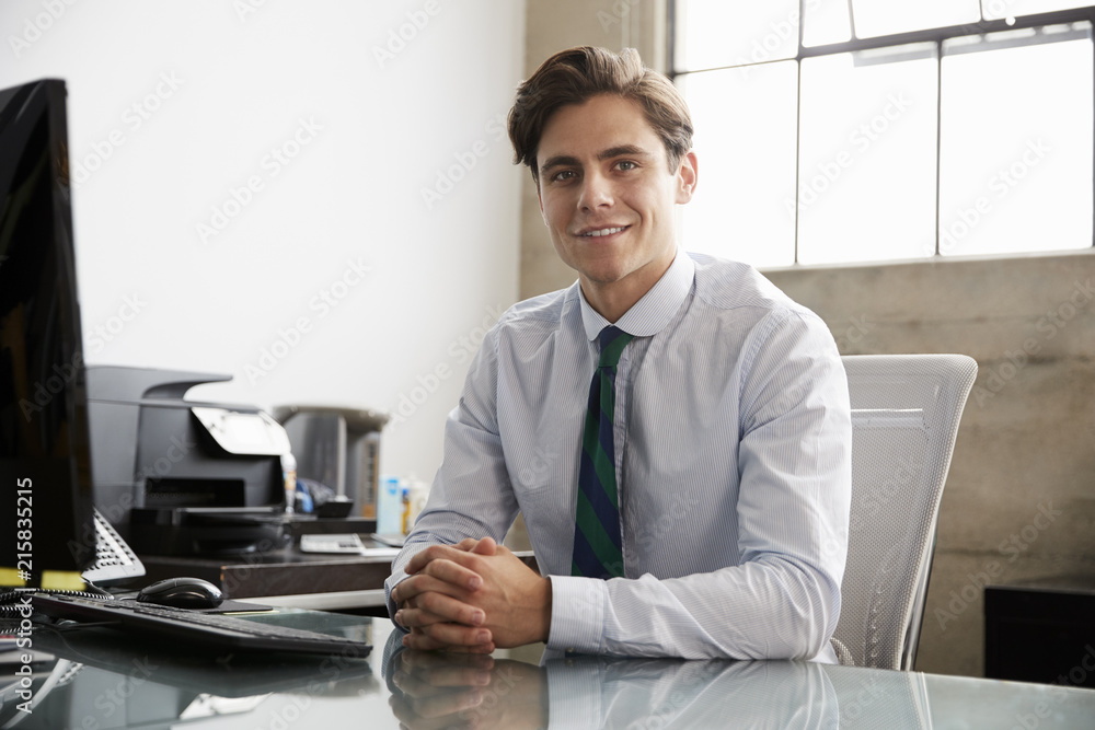 Young white businessman at an office desk, smiling to camera Young white businessman at an office desk, smiling to camera