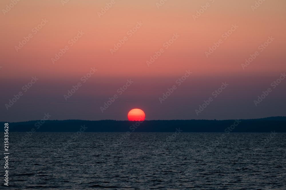 Big red sun rising over lake scene