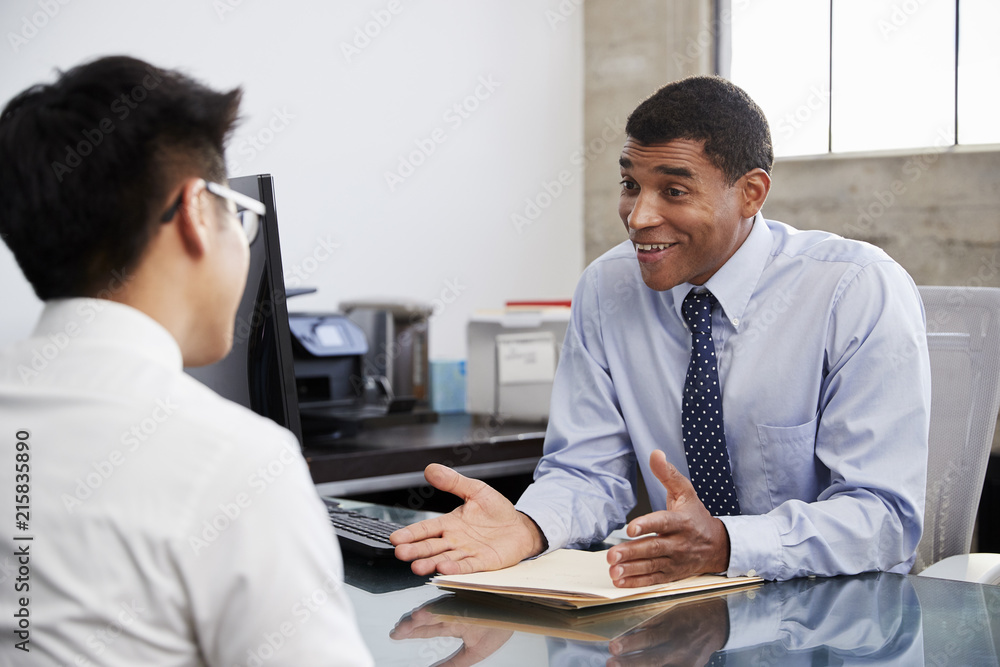 Mixed race male professional in meeting with young Asian man Mixed race male professional in meeting with young Asian man