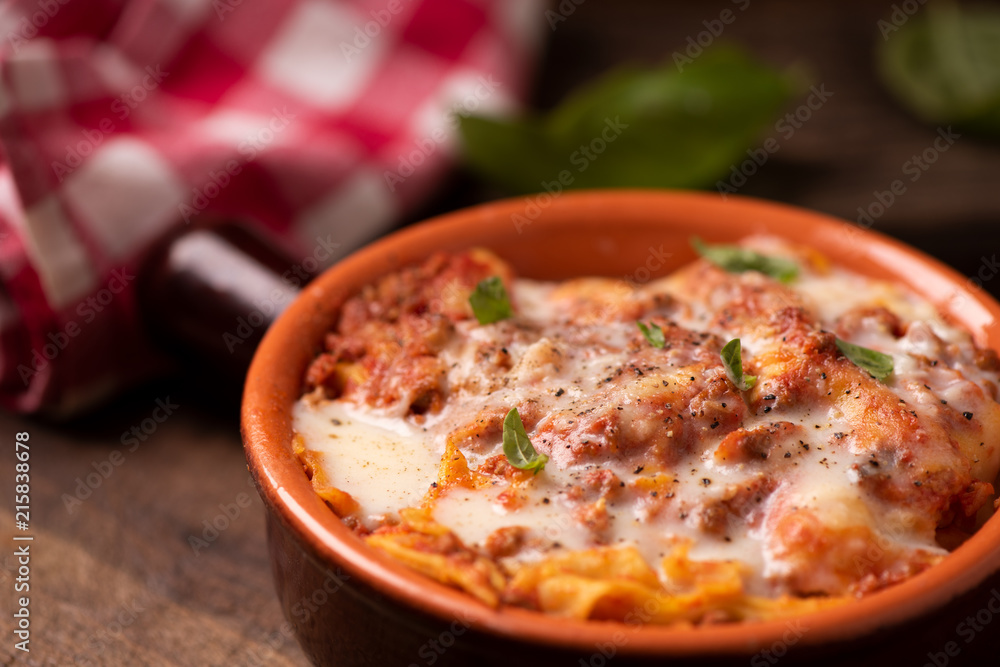 Traditional lasagne in a casserole dish on wooden table Traditional lasagne in a casserole dish on wooden table