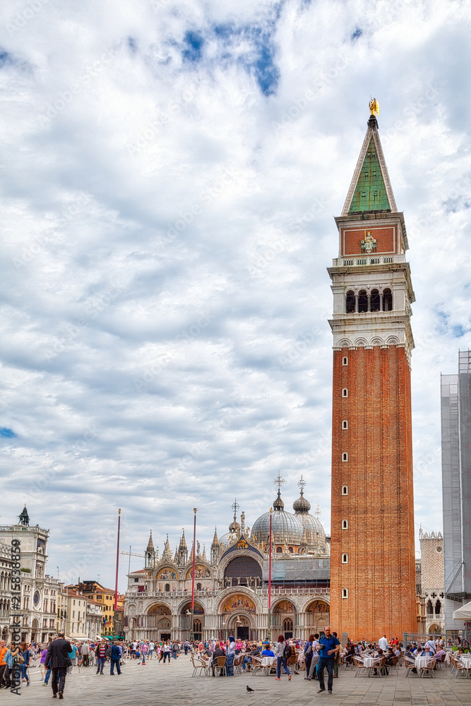 Obraz premium Der Markusplatz in Venedig mit der Basilika San Marco, dem Uhrenturm und Dogenpalast, umschlossen von den alten und neuen Prokuratien, mit vielen Touristen