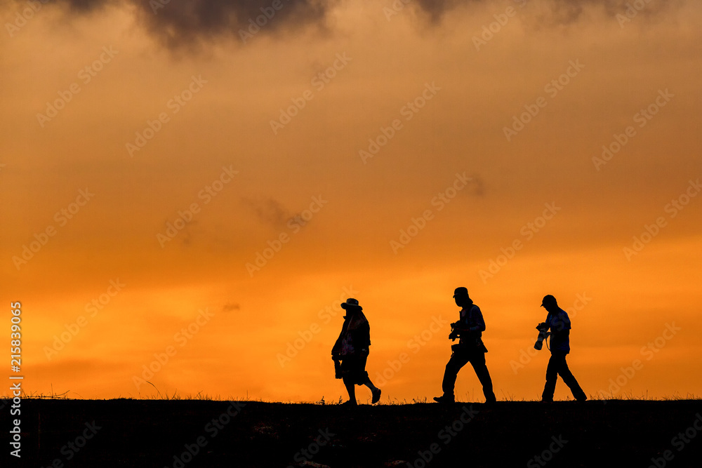 silhouette of photographer group walking with camera for taking photo during sunset