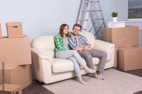 Home, people and moving concept- Attractive young couple sit sit on the couch