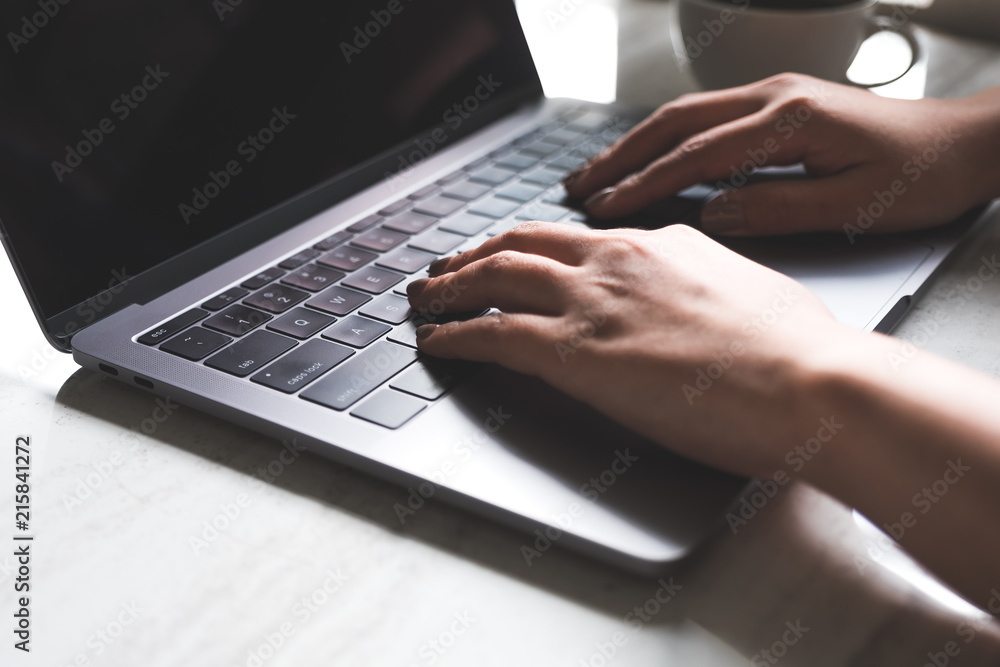 Closeup image of a woman working and typing on laptop keyboard with coffee cup on the table Closeup image of a woman working and typing on laptop keyboard with coffee cup on the table