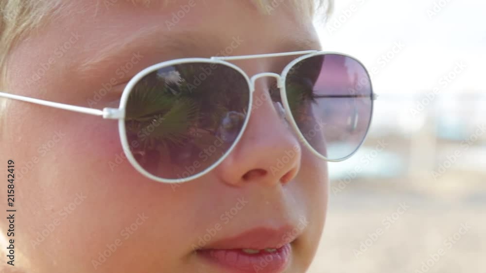 Closeup portrait of cute little kid wearing sunglasses standing on summer beach in Turkey. Real time full hd video footage. Closeup portrait of cute little kid wearing sunglasses standing on summer beach in Turkey. Real time full hd video footage.