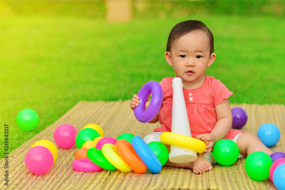 Obraz premium Cute Asian baby playing with toys in playground 