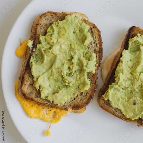 Breakfast toasts with avocado, egg and whole grain quinoa bread on white plate, healthy eating