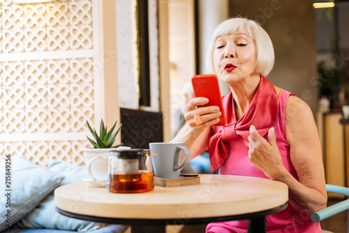 Online connection. Joyful age woman holding he smartphone while having a video call