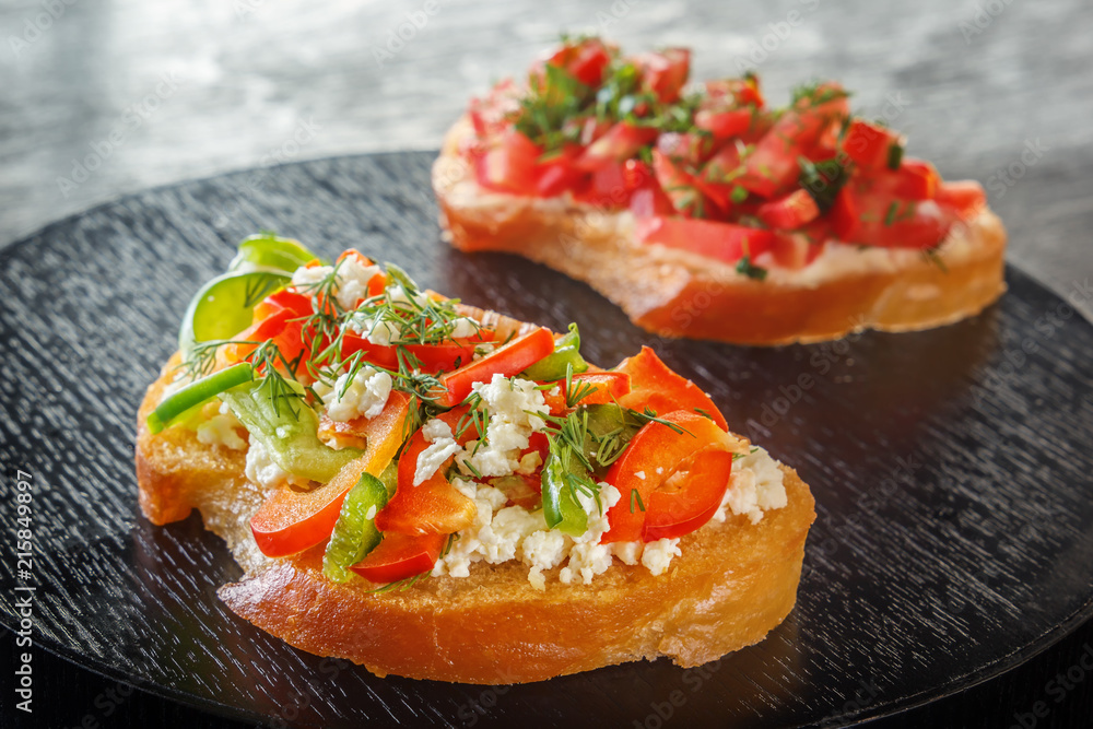 Bruschetta with red sweet pepper and goat cheese on a black background. Close-up Bruschetta with red sweet pepper and goat cheese on a black background. Close-up