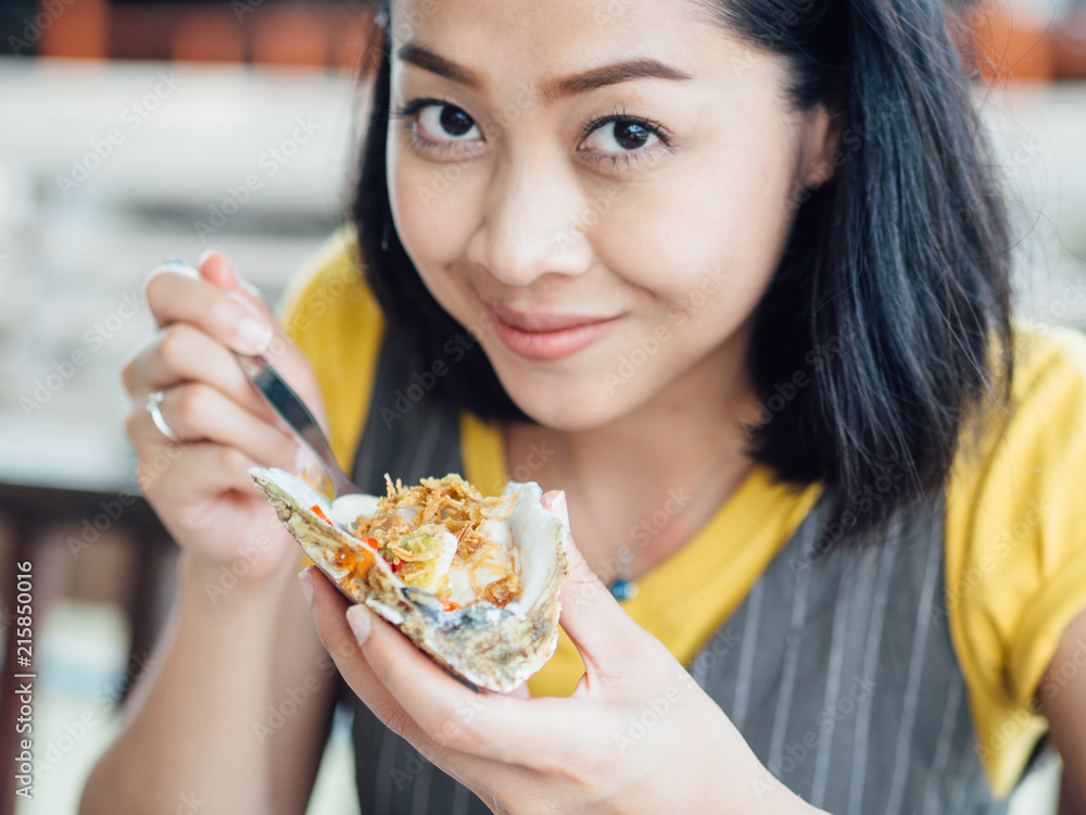 Woman eats Thai style fresh oyster with garlic. Woman eats Thai style fresh oyster with garlic.