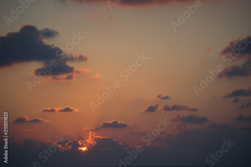 Fototapeta Naklejka Na Ścianę i Meble -  Extreme zoom photo of tropical summer sunset with huge sun lost in clouds with beautiful red and golden colours