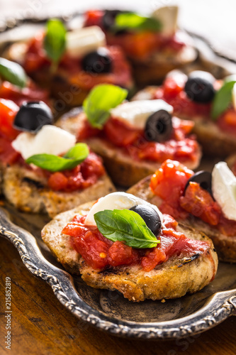 Bruschetta toast with mozzarella tomatoes olives and basil.