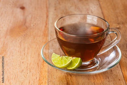 a cup of lime tea on wooden table, hot drink with steam