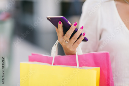 A cheerful girl with a phone, a bank card and shopping in the mall. Quickly and easily make an order online, pay, get a profitable offer