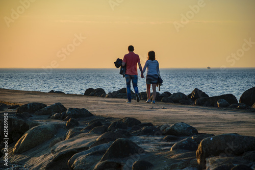people enjoying sunset on the brakewater in the sea photo