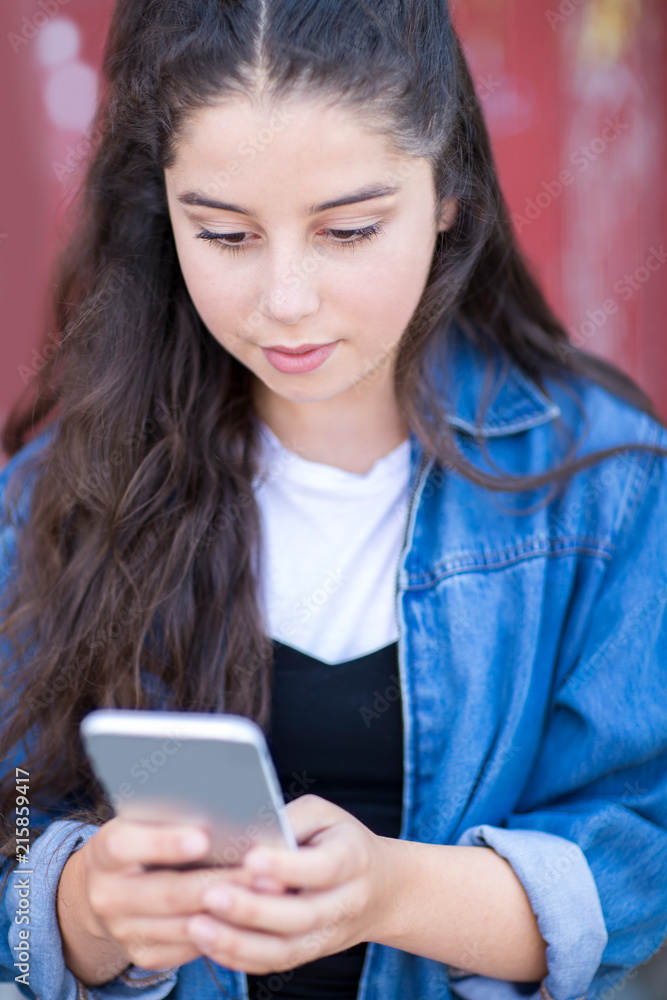 Teenage Girl Texting On Mobile Phone In Urban Setting