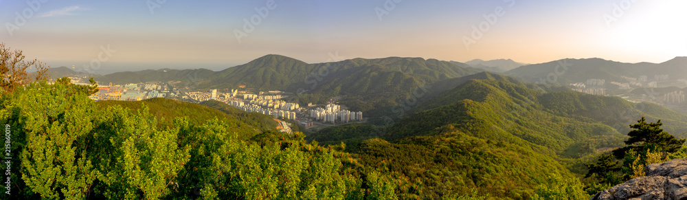 Obraz premium Panoramic top view of Guksabong mountain. View from its peak, It has mountain ridge with city and shipyard on the leftside.Fog sky in the evening.