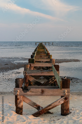 Old wooden pier and  ocean in background at sunset © Martina
