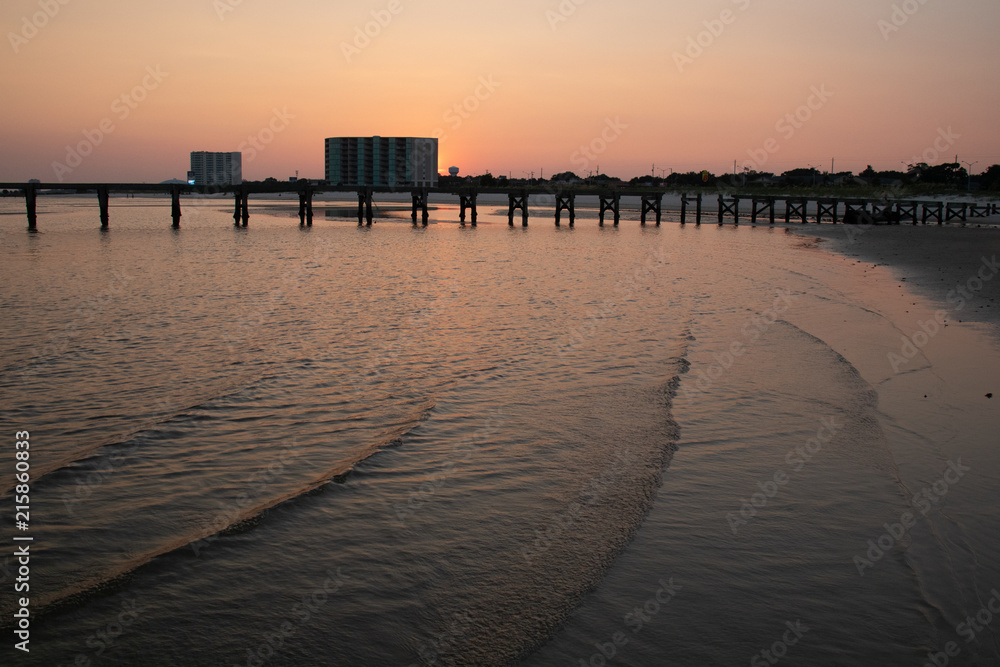 Obraz premium Old wooden pier and ocean in foreground at sunset