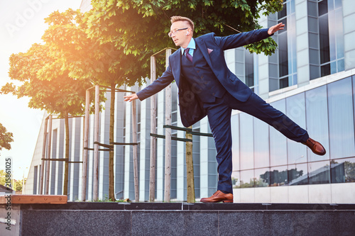 Stylish businessman dressed in an elegant suit have fun while standing outdoors against a skyscraper background.