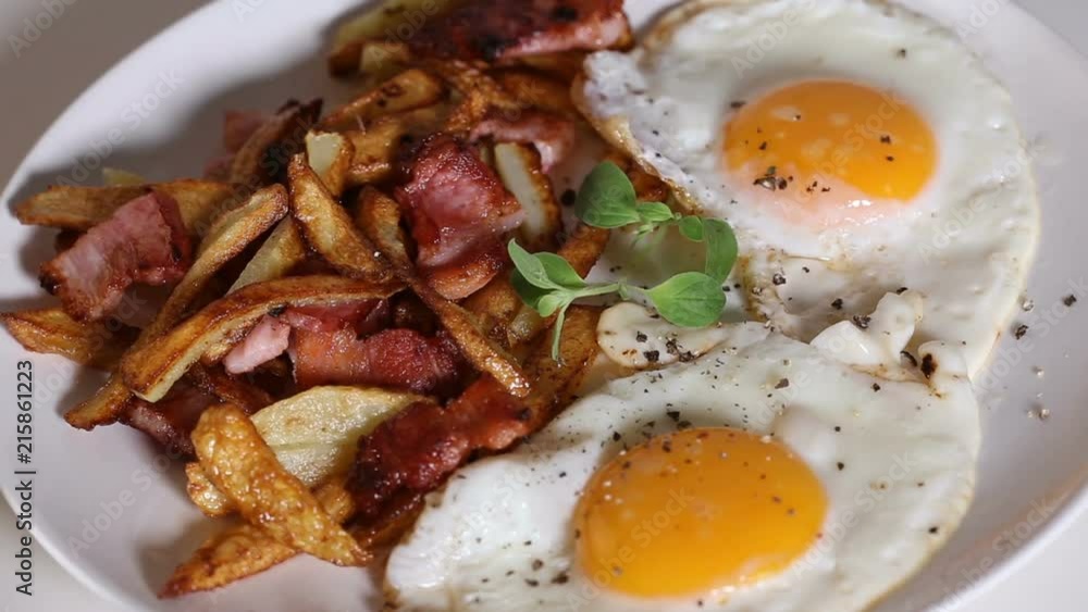 Spreading ground black pepper over fried eggs, fires and fried bacon Spreading ground black pepper over fried eggs, fires and fried bacon