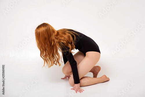 portrait of a beautiful girl on a white background with red hair doing gymnastic exercises.