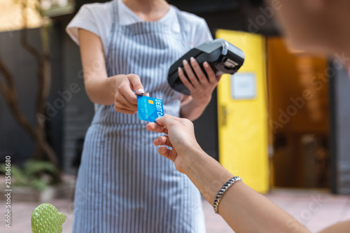 Card payment. Modern prosperous businesswoman paying for her lunch by card while giving it to waitress